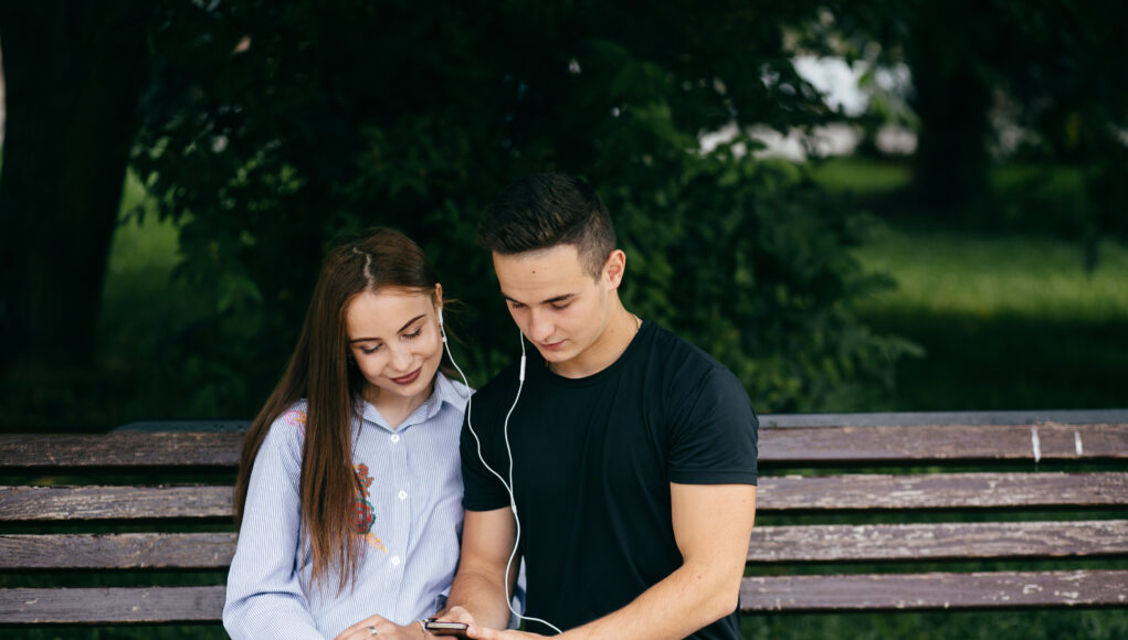 company of young friends with smartphones walking in city
